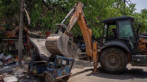 A bulldozer slams an auto rickshaw during the demolition of Muslim-owned shops in the area that saw communal violence during a Hindu religious procession on Saturday, in New Delhi's northwest Jahangirpuri neighborhood, in New Delhi, India, Wednesday, April 20, 2022 - Sputnik International
