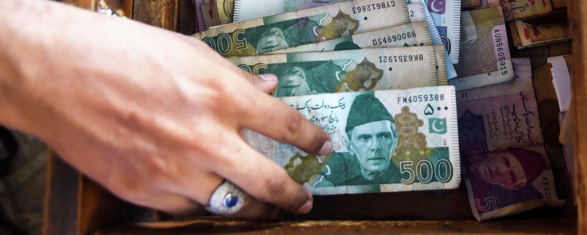 A Pakistani man counts Pakistan's rupees at his shop in Karachi on May 16, 2019 - Sputnik International, 1920, 19.05.2022