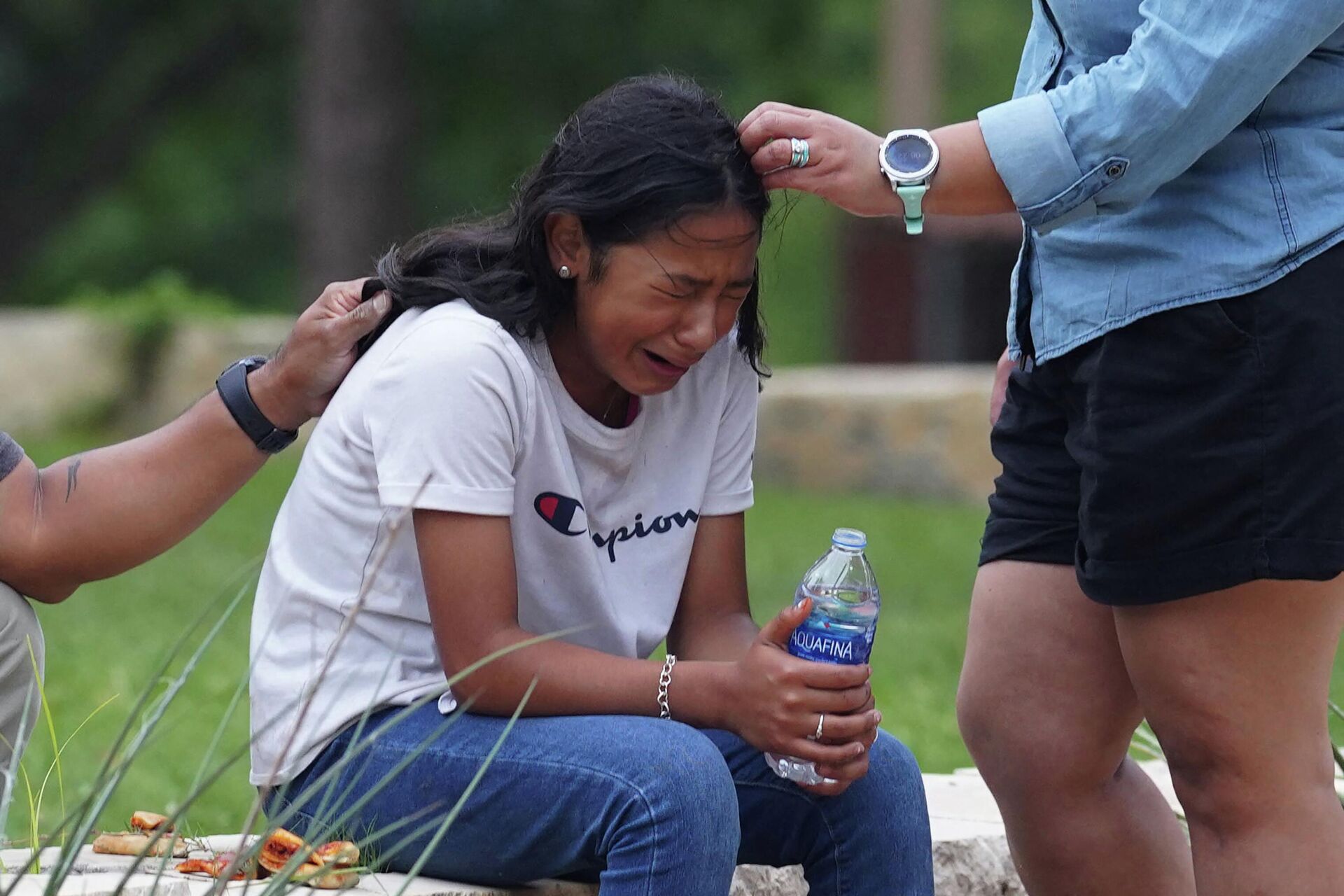 A girl cries, comforted by two adults, outside the Willie de Leon Civic Center where grief counseling will be offered in Uvalde, Texas, on May 24, 2022. - A teenage gunman killed 18 young children in a shooting at an elementary school in Texas on Tuesday, in the deadliest US school shooting in years. - Sputnik International, 1920, 25.05.2022