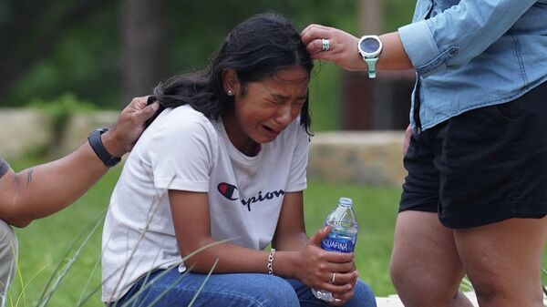 A girl cries, comforted by two adults, outside the Willie de Leon Civic Center where grief counseling will be offered in Uvalde, Texas, on May 24, 2022. - A teenage gunman killed 18 young children in a shooting at an elementary school in Texas on Tuesday, in the deadliest US school shooting in years. - Sputnik International
