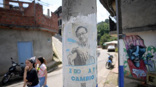 People walk near propaganda depicting Colombian left-wing presidential candidate Gustavo Petro  at the Siloe shantytown in Cali, Colombia, on May 24, 2022. - Sputnik International