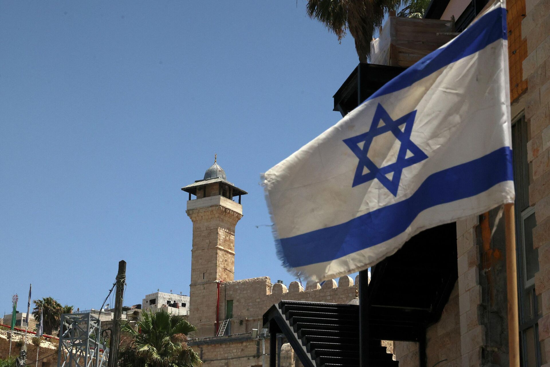 An Israeli flag flies in a street in front of the Ibrahimi Mosque or the Tomb of the patriarches, in the occupied West Bank town of Hebron, on May 26, 2022. - Sputnik International, 1920, 06.06.2022