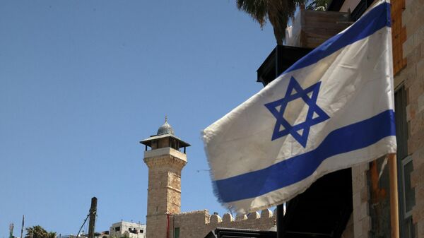 An Israeli flag flies in a street in front of the Ibrahimi Mosque or the Tomb of the patriarches, in the occupied West Bank town of Hebron, on May 26, 2022. - Sputnik International