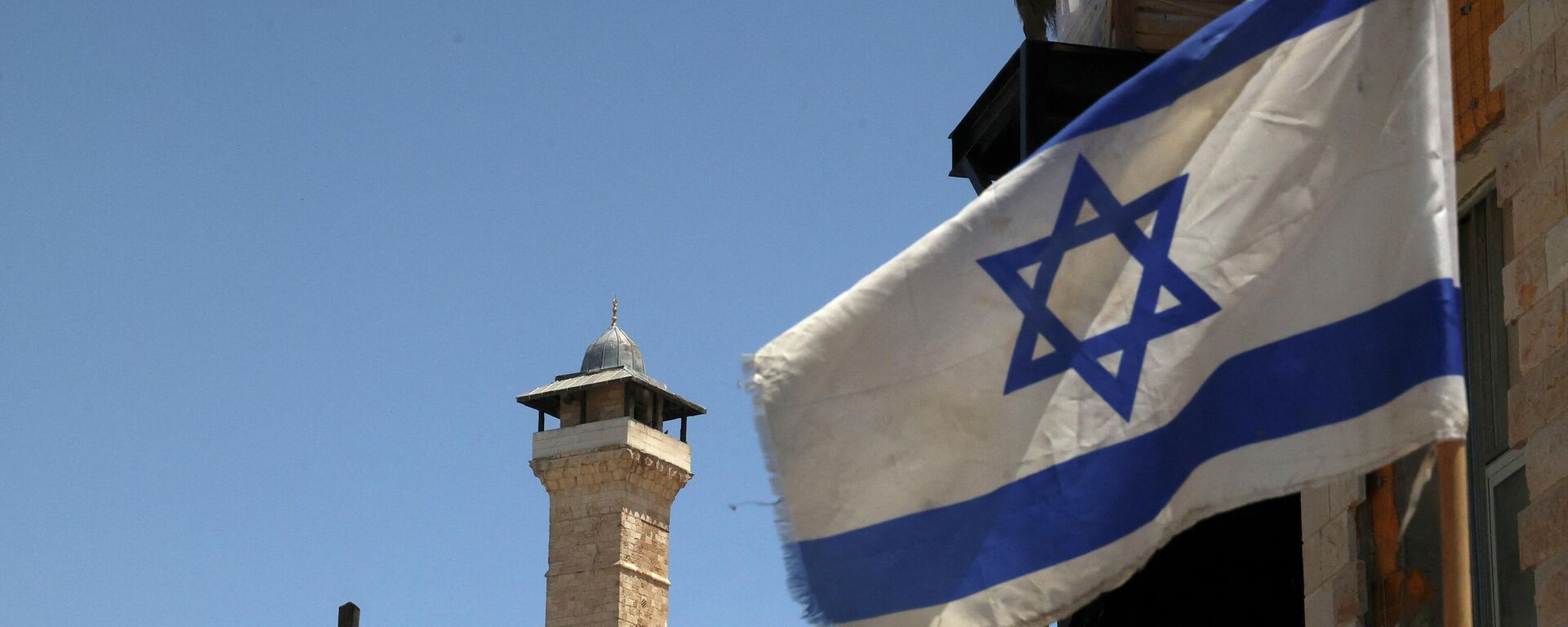 An Israeli flag flies in a street in front of the Ibrahimi Mosque or the Tomb of the patriarches, in the occupied West Bank town of Hebron, on May 26, 2022. - Sputnik International, 1920, 07.06.2022
