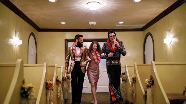 Elvis impersonator Brendan Paul, right, walks down the isle during a wedding ceremony for Katie Salvatore, center, and Eric Wheeler at the Graceland Wedding Chapel on Valentine's Day, Thursday, Feb. 14, 2019, in Las Vegas. - Sputnik International