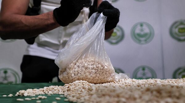 An officer of the Directorate of Narcotics Control of Saudi Arabia's Interior Ministry empties a bag of tablets of captagon (Fenethylline) seized during a special operation and presented before AFP afterwards in the Red Sea coastal city of Jeddah on March 1, 2022.  - Sputnik International