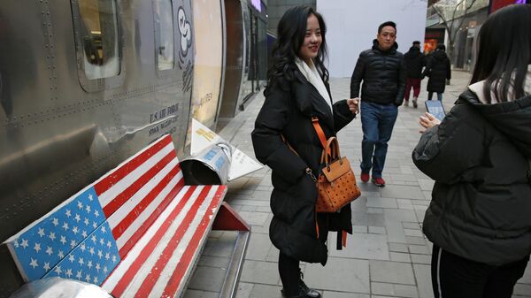 In this Sunday, Jan. 6, 2019, photo, Chinese shoppers spend their time next to a bench painted with the U.S. flag at the capital city's popular shopping mall in Beijing - Sputnik International