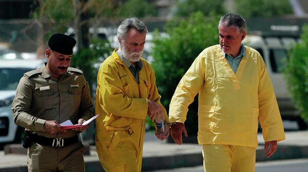 Volker Waldmann, right, and Jim Fitton, center, are handcuffed as they walk to a courtroom in Baghdad, Iraq, Sunday, May 22, 2022 - Sputnik International