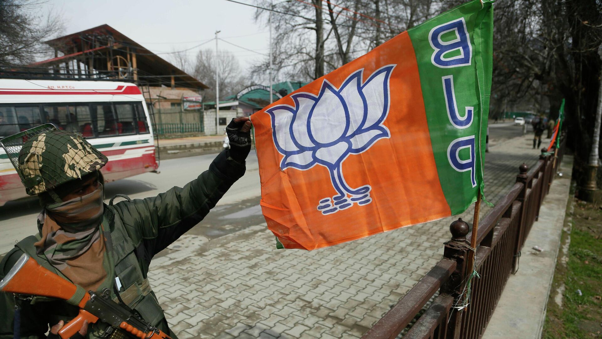 An Indian paramilitary soldier holds a flag of India's ruling Bharatiya Janata Party (BJP) as he stands guard during a meeting of the party ahead of the upcoming elections in Srinagar, Indian controlled Kashmir, Thursday, March 14, 2019 - Sputnik International, 1920, 21.06.2022