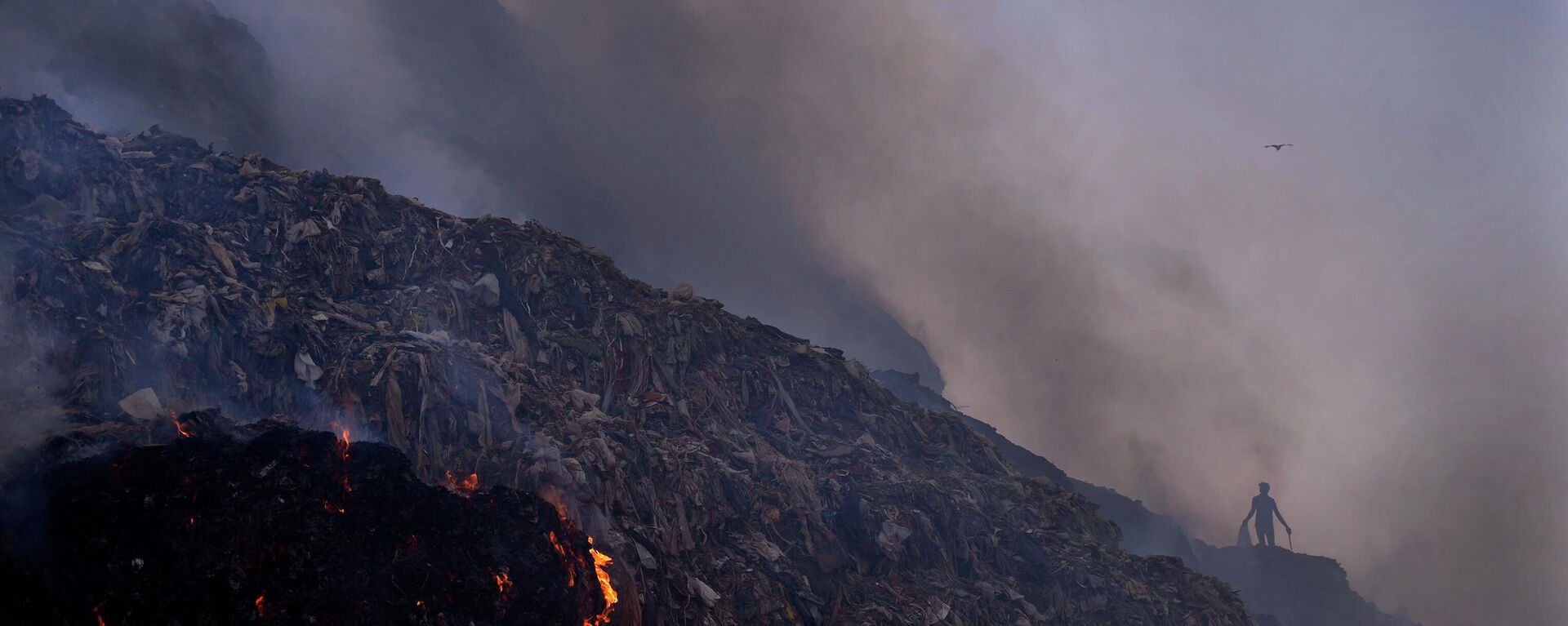 A ragpicker looks for reusable items while a fire rages at the Bhalswa landfill in New Delhi, Wednesday, April 27, 2022 - Sputnik International, 1920, 24.06.2023