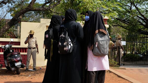 An Indian Muslim student wearing school uniform and hijab listens to fellow students wearing burqas after they were denied entry into the campus of Mahatma Gandhi Memorial college in Udupi, Karnataka state, India, Thursday, Feb. 24, 2022 - Sputnik International