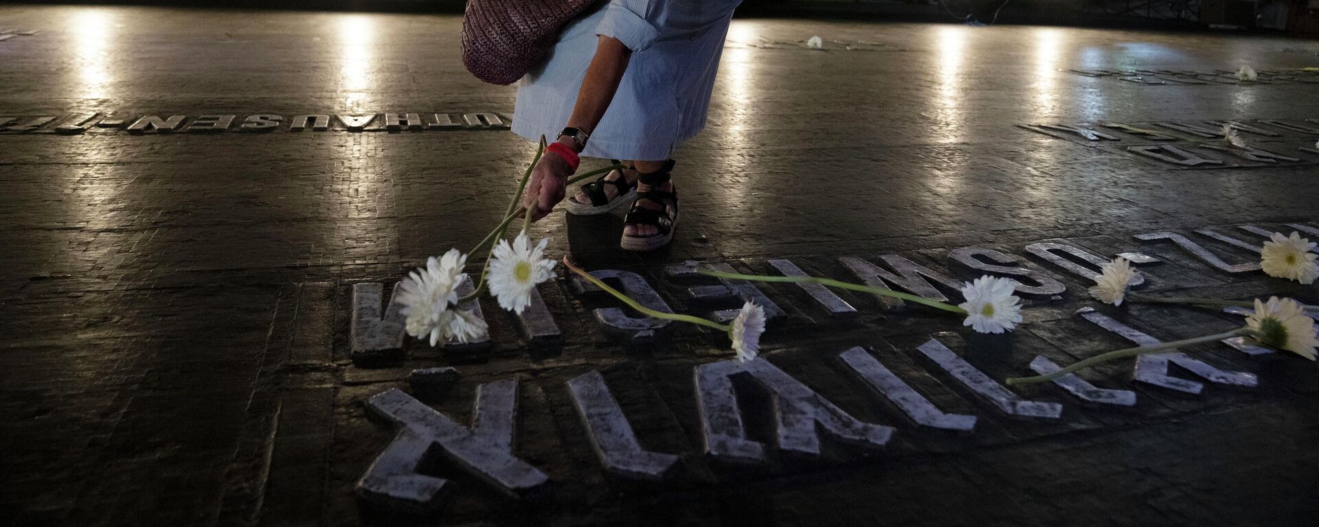 A woman places a flower on a marker for the Auschwitz concentration camp in the Hall of Remembrance during the Holocaust Martyrs and Heroes Remembrance Day at the Yad Vashem Holocaust Museum in Jerusalem, Thursday, April 28, 2022. (AP Photo/Maya Alleruzzo) - Sputnik International, 1920, 08.06.2022