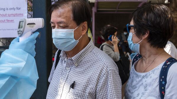 A health worker checks the temperatures of visitor at the entrance of a Community Testing Centre in Hong Kong, China. After days of rapidly increase of positive COVID-19 cases, the Hong Kong government set up testing facility centers where people can be tested for COVID-19 and obtain the result within 24 hours. - Sputnik International