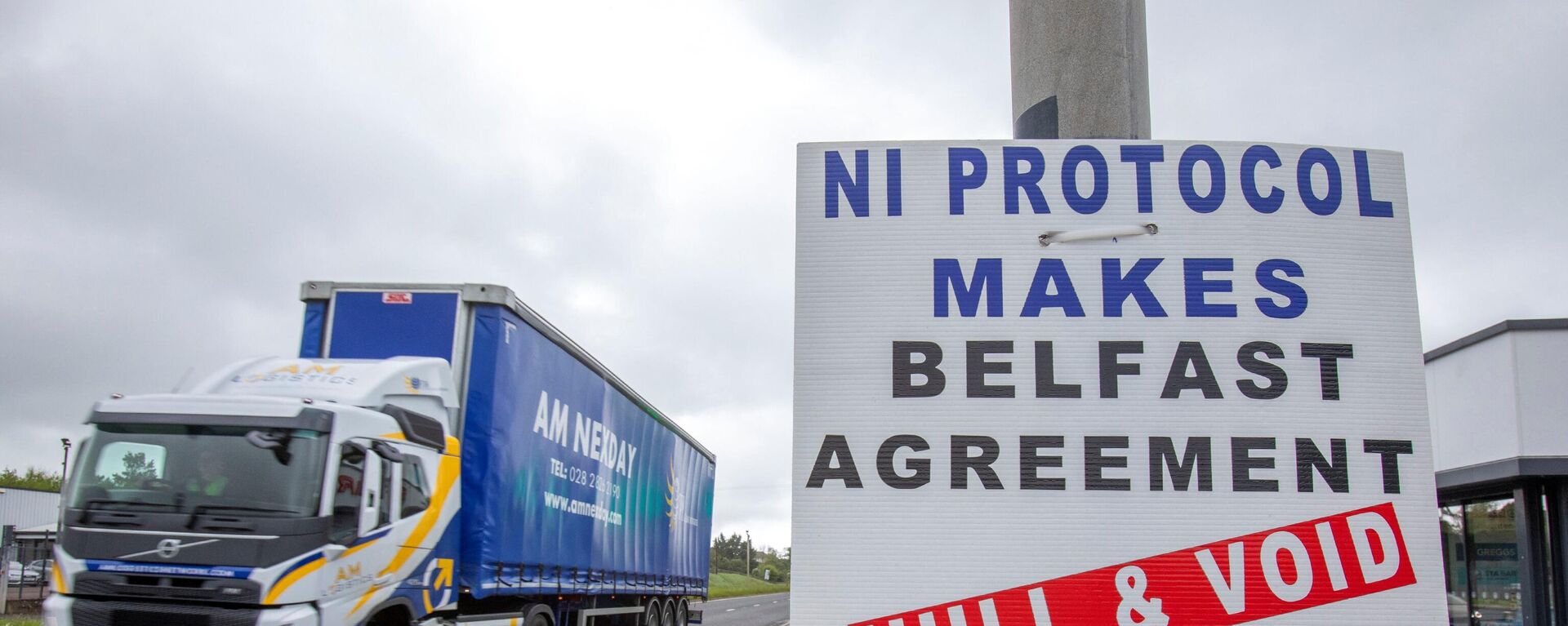 A lorry passes an anti 'Northern Ireland Protocol' sign as it is driven away from Larne port, north of Belfast in Northern Ireland, after arriving on a ferry, on May 17, 2022. - Sputnik International, 1920, 13.06.2022