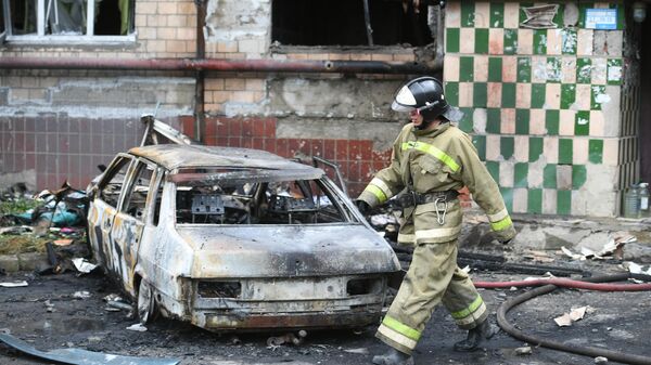 An employee of the Ministry of Emergency Situations of the DPR near a residential building that burned down as a result of shelling of Donetsk by the Armed Forces of Ukraine. - Sputnik International