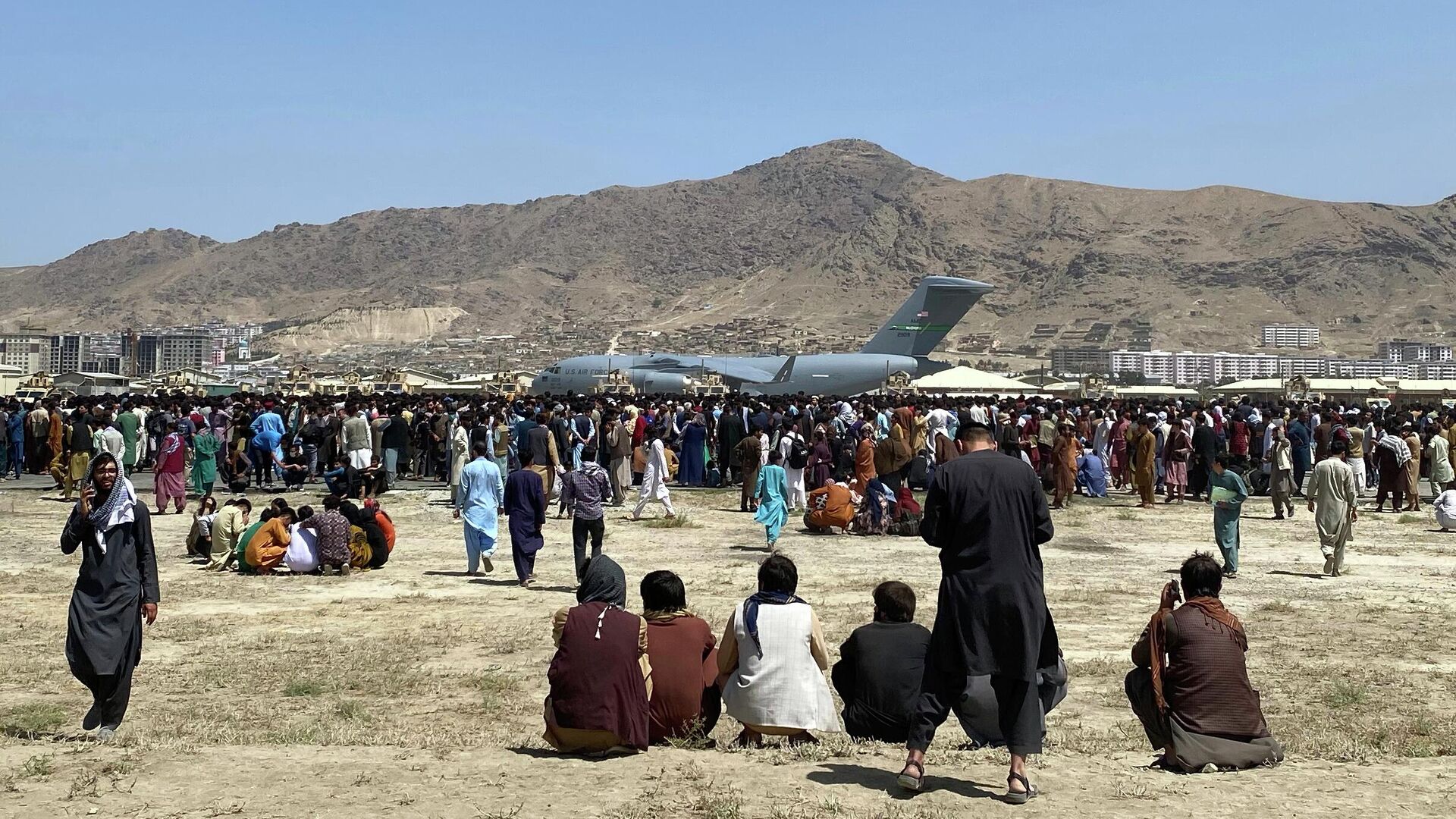  In this Aug. 16, 2021, file photo, hundreds of people gather near a U.S. Air Force C-17 transport plane at the perimeter of the international airport in Kabul, Afghanistan. Ordinary Americans and the nation's airlines are combining to donate miles and cash to help Afghan refugees resettle in the United States. Organizers said Tuesday, Oct. 26, they have raised enough donations pay for 40,000 flights, but they're hoping to nearly double that amount.  - Sputnik International, 1920, 14.06.2022