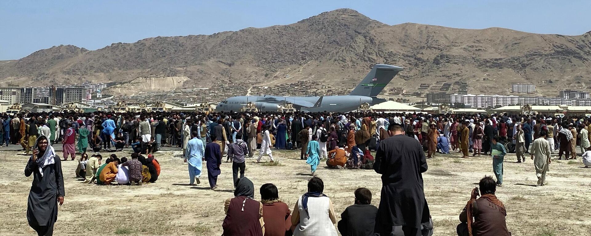  In this Aug. 16, 2021, file photo, hundreds of people gather near a U.S. Air Force C-17 transport plane at the perimeter of the international airport in Kabul, Afghanistan. Ordinary Americans and the nation's airlines are combining to donate miles and cash to help Afghan refugees resettle in the United States. Organizers said Tuesday, Oct. 26, they have raised enough donations pay for 40,000 flights, but they're hoping to nearly double that amount.  - Sputnik International, 1920, 12.08.2022