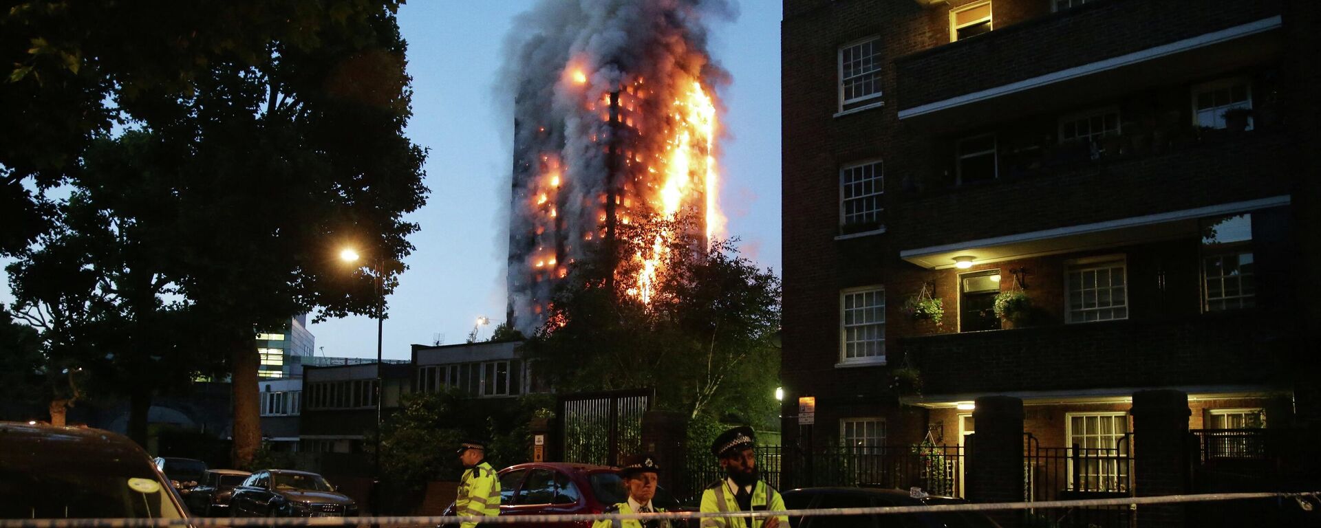 (FILES) In this file photo taken on June 14, 2017 police man stand by a security cordon as a huge fire engulfs the Grenfell Tower early, in west London - Sputnik International, 1920, 14.06.2022