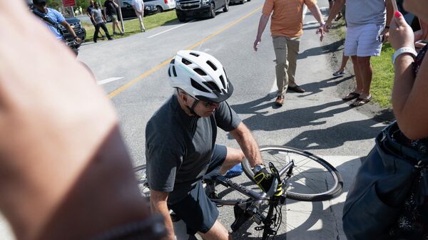 US President Joe Biden falls off his bicycle as he approaches well-wishers following a bike ride at Gordon's Pond State Park in Rehoboth Beach, Delaware, on June 18, 2022 - Sputnik International