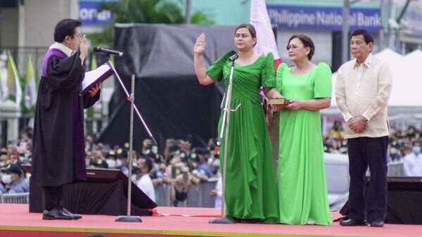 Philippines' Vice President-elect Sara Duterte (C) takes her oath before supreme court associate justice Ramon Hernando (L) and her mother Elizabeth Zimmerman (2nd R) and outgoing president Rodrigo Duterte (R) during the inauguration ceremony near the city hall in Davao City on June 19, 2022.  - Sputnik International