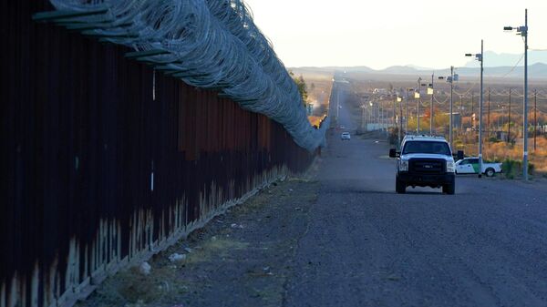 A U.S. Border Patrol vehicle drives along the border fence at the U.S.-Mexico border wall, on Dec. 15, 2020, in Douglas, Ariz. Authorities are investigating the cause of death of a female migrant whose leg was entrapped while using a climbing harness and ended up hanging upside down off the border wall in eastern Arizona. U.S. Customs and Border Protection officials offered few details, but the local sheriff's office said the woman was a 32-year-old Mexican who was attempting to cross the wall Monday, April 11, 2022 near Douglas, Arizona. Her name was not released. - Sputnik International