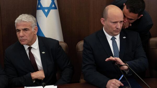 Israeli Prime Minister Naftali Bennett (R) listens to an aide as Foreign Minister Yair Lapid looks on during the weekly cabinet meeting in Jerusalem, on May 8, 2022 - Sputnik International