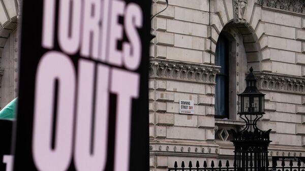 The road sign of Downing Street seen behind a placard reading 'Tories out', during a protest against the increase of the cost of living, in London, Saturday, April 2, 2022. - Sputnik International