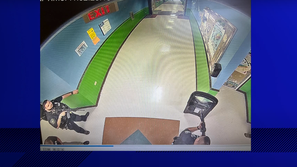 Screengrab of security camera footage from inside Robb Elementary School on the day of last month's schooting showing officers equipped with automatic rifles and at least one shield.  - Sputnik International