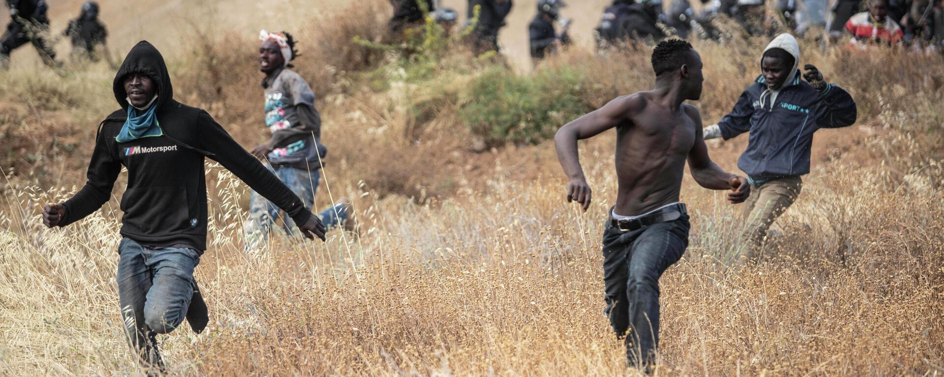 Migrants run on Spanish soil after crossing the fences separating the Spanish enclave of Melilla from Morocco in Melilla, Spain, Friday, June 24, 2022 - Sputnik International, 1920, 24.06.2022