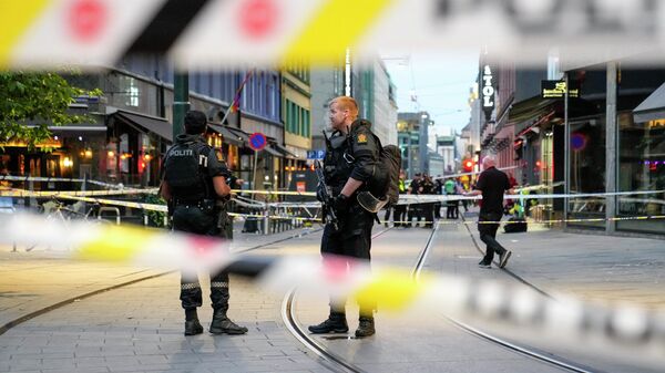 Norwegian police officers stand guard in the streets of central Oslo between security tape lines, on June 25, 2022, after shots were fired outside the London pub, killing two people. - Sputnik International