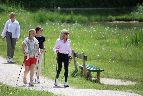 French President's wife Brigitte Macron (R) and EU Council President's wife Amelie Derbaudrenghien (C) take part in a Nordic Walk with former German biathlete Miriam Neureuther carrying a baby as part of the spouses program on the sidelines of the G7 Summit in Mittenwald, southern Germany, on June 26, 2022.  - Sputnik International