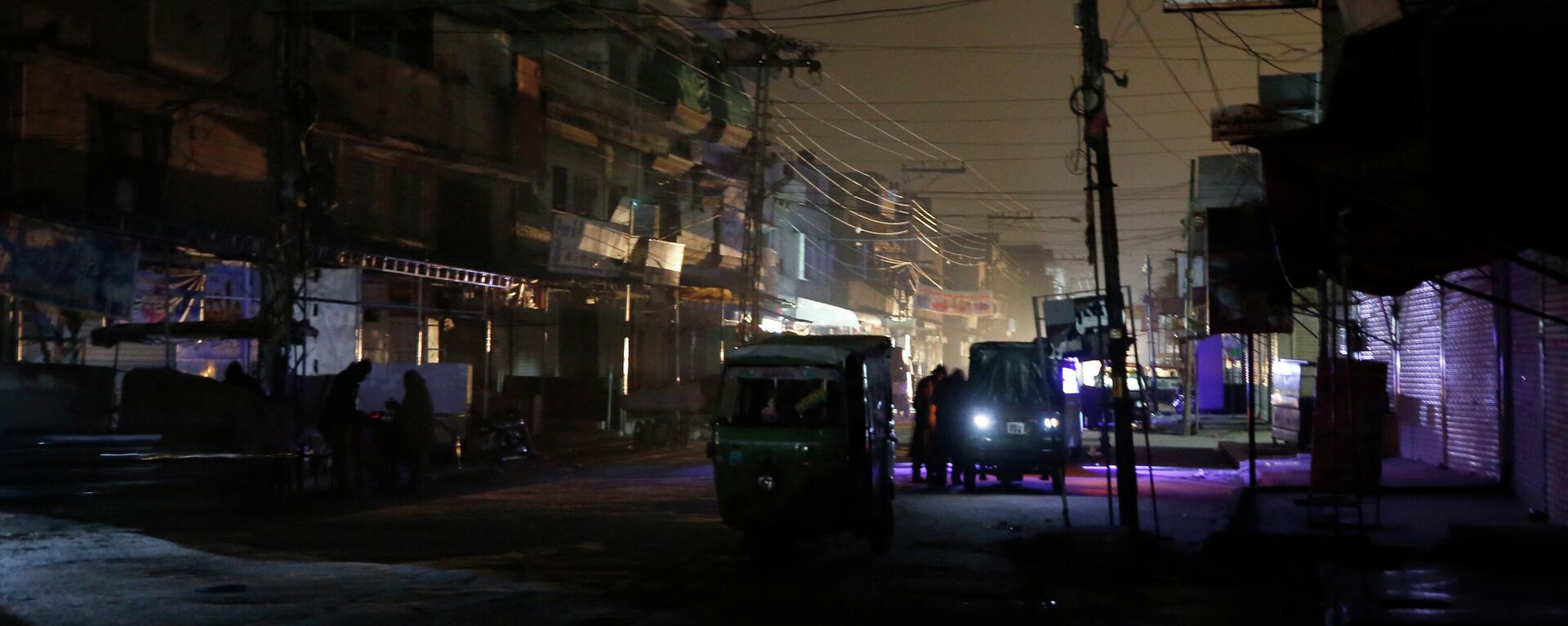 People and auto rickshaws are silhouetted on vehicles headlights on a dark street during widespread power outages in Rawalpindi, Pakistan, Sunday, Jan. 10, 2021. - Sputnik International, 1920, 01.07.2022