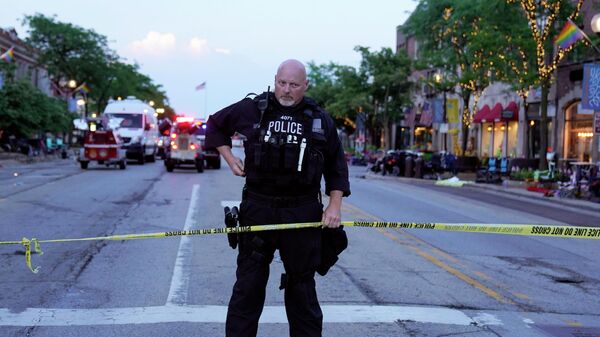 A police officer holds up police tape at the scene of a mass shooting at the Highland Park Fourth of July parade in downtown Highland Park, a Chicago suburb, on Monday, July 4, 2022. (AP Photo/Nam Y. Huh) - Sputnik International