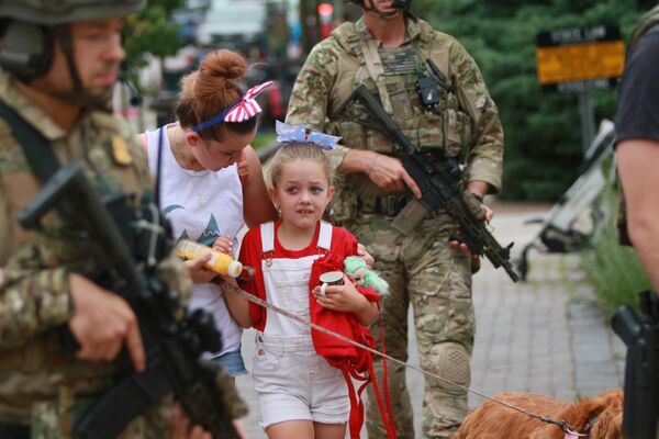 Law enforcement escorts a family away from the scene of a shooting at a Fourth of July parade on July 4, 2022 in Highland Park, Illinois. - Sputnik International