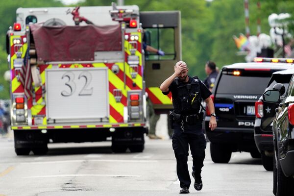 A police officer reacts as he walks in downtown Highland Park, a suburb of Chicago, Ill., Monday, July 4, 2022, where a mass shooting took place at the Highland Park Fourth of July parade. - Sputnik International
