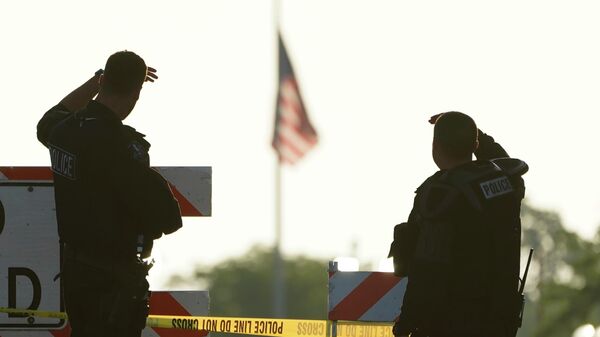 Two police officers stand their post, the day after a deadly mass shooting on the Westside of the Highland Park, Ill.,  Tuesday, July 5, 2022, as the American flag flies at half-staff on the Eastside.   - Sputnik International