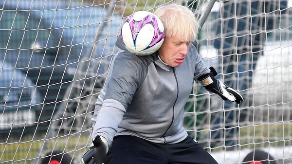 Премьер-министр Великобритании Борис Джонсон пытается отразить удар во время разминки перед футбольным матчем среди девочек во время предвыборной кампании в Чидл-Халме, на северо-западе Англии, 2019 год - Sputnik International