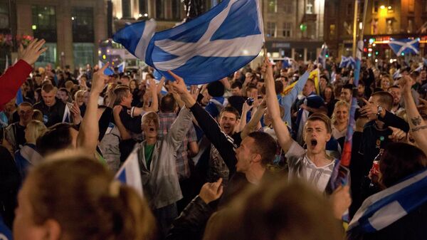 Supporters of the Yes campaign in the Scottish independence referendum wave Scottish Saltire flags as they await the result after the polls closed, in Glasgow, Scotland. - Sputnik International