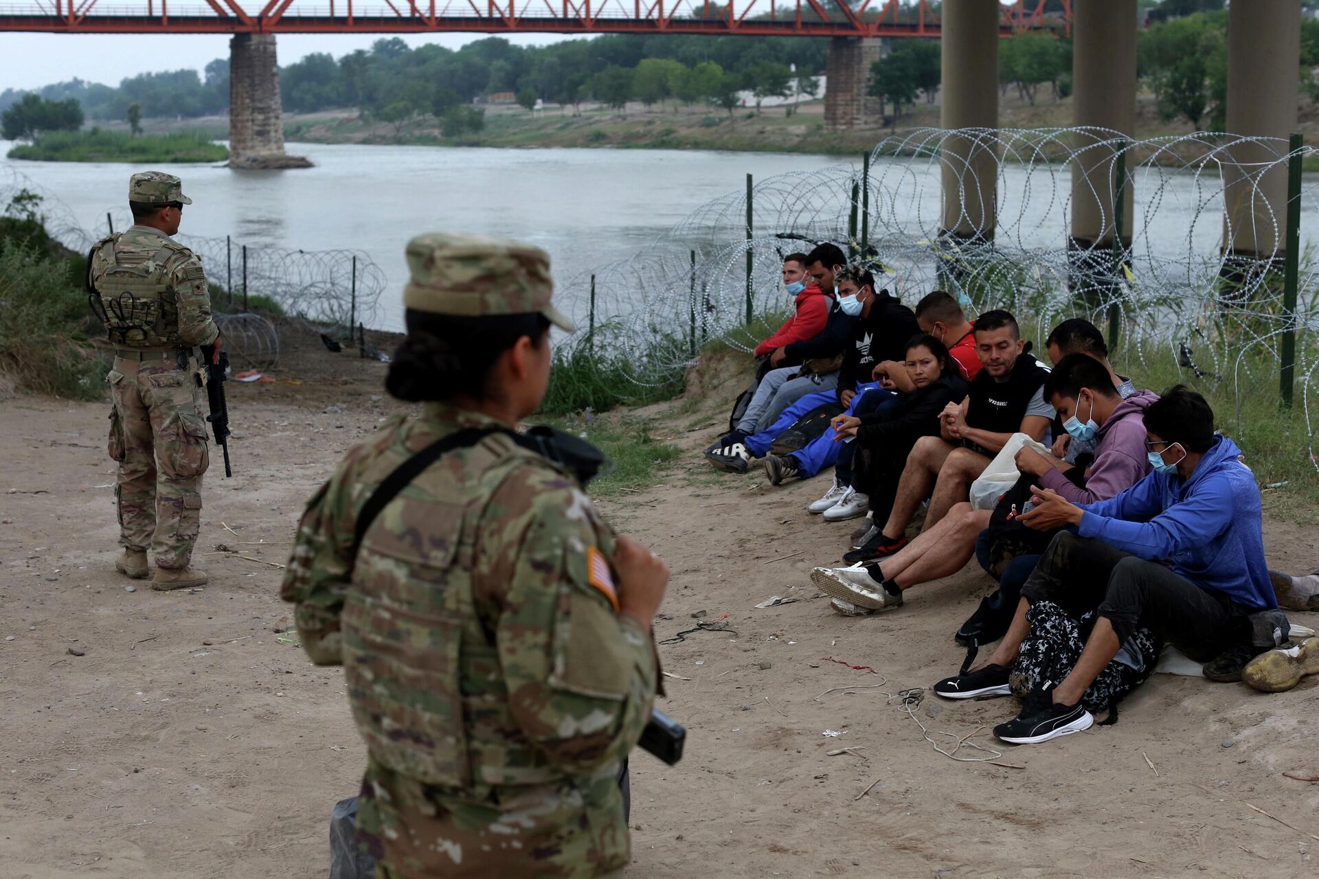 Migrants who had crossed the Rio Grande river into the U.S. are under custody of National Guard members as they await the arrival of U.S. Border Patrol agents in Eagle Pass, Texas, Friday, May 20, 2022 - Sputnik International, 1920, 10.07.2022
