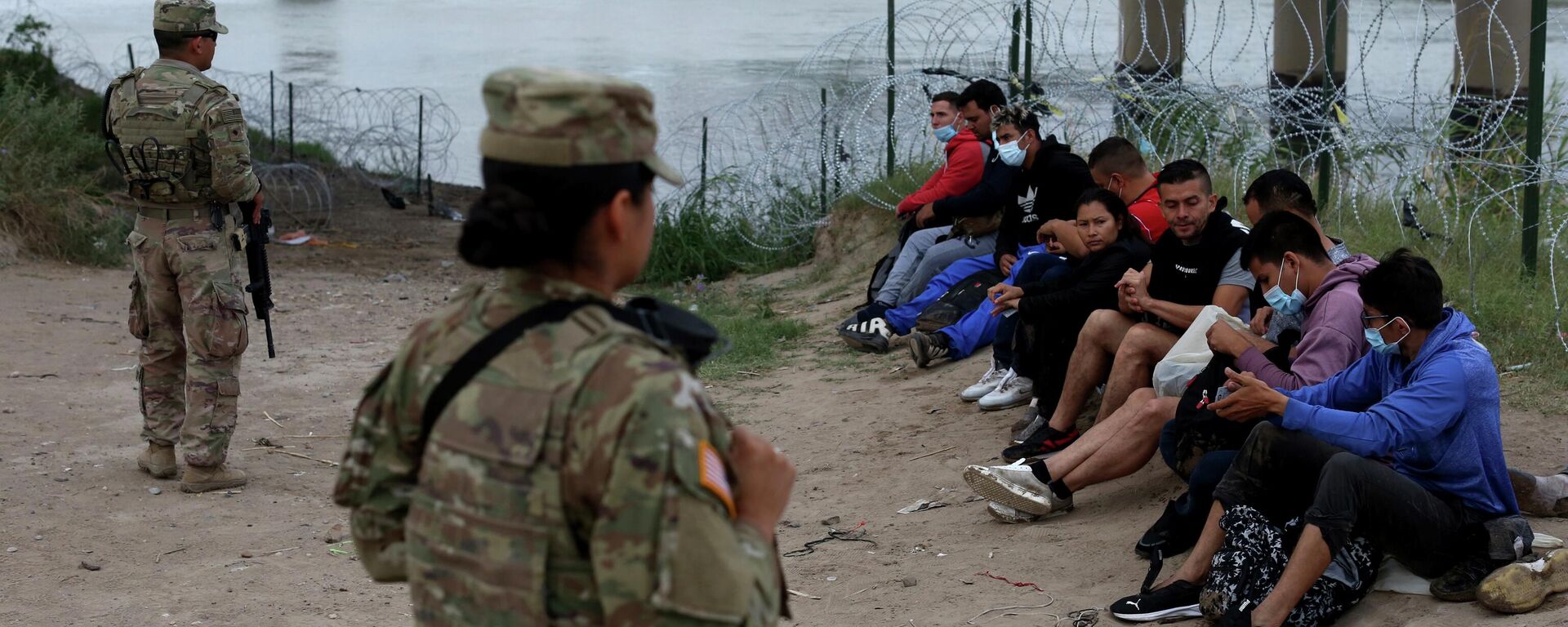 Migrants who had crossed the Rio Grande river into the U.S. are under custody of National Guard members as they await the arrival of U.S. Border Patrol agents in Eagle Pass, Texas, Friday, May 20, 2022 - Sputnik International, 1920, 08.07.2022