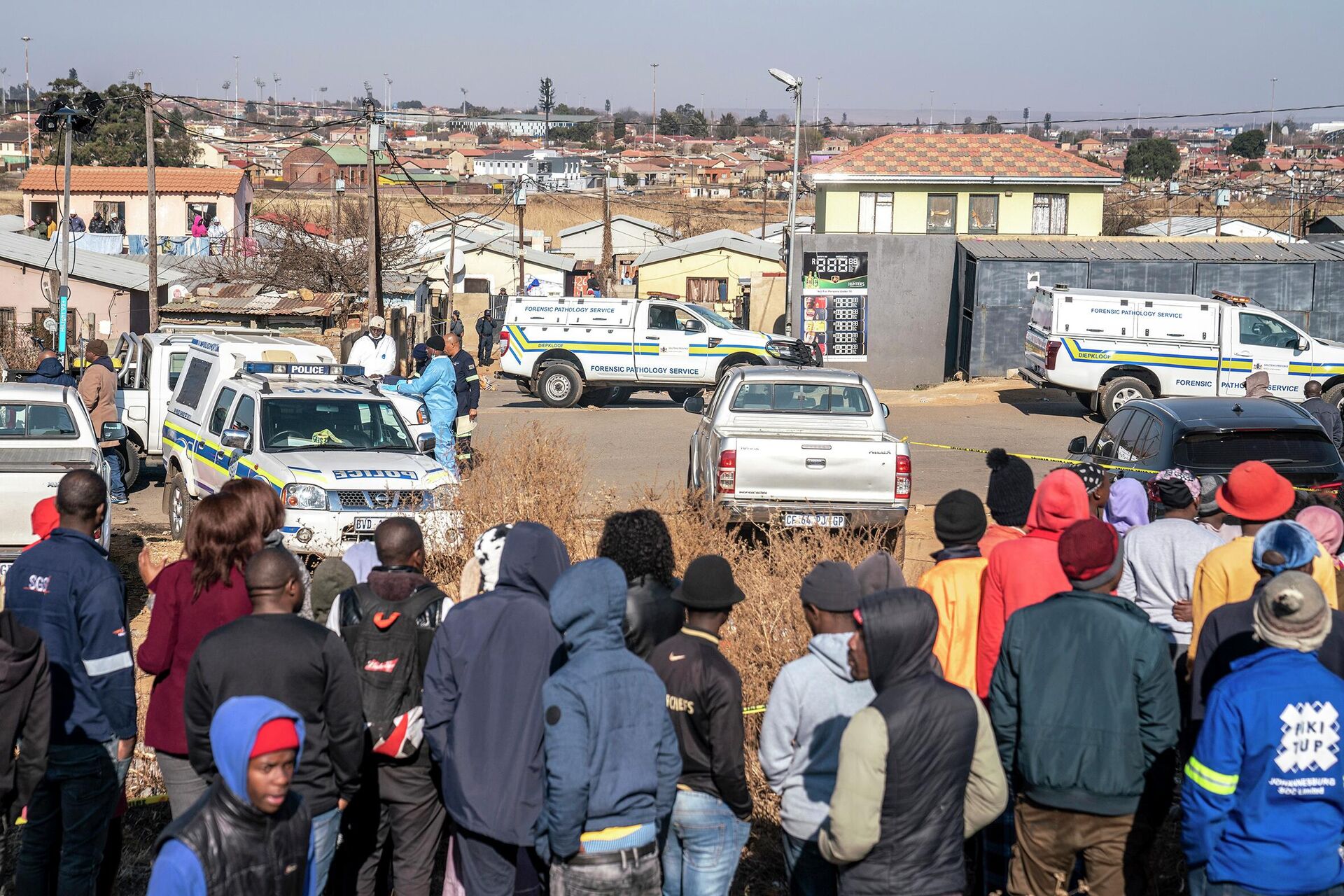 People gather at the scene of an overnight bar shooting in Soweto, South Africa, Sunday July 10, 2022. A mass shooting at a tavern in Johannesburg's Soweto township has killed 15 people and left others in critical condition, according to police. Police say they are investigating reports that a group of men arrived in a minibus taxi and opened fire on some of the patrons at the bar shortly after midnight Sunday.   - Sputnik International, 1920, 11.07.2022