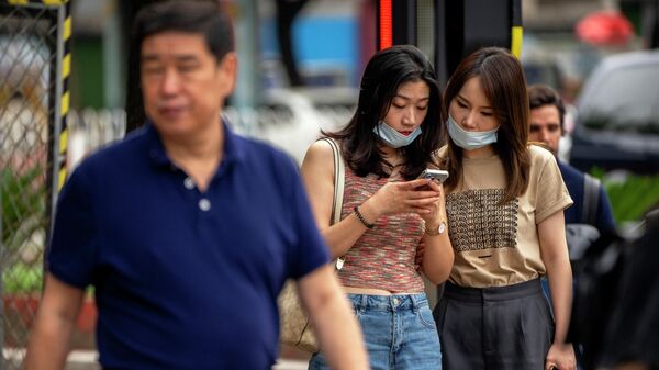 Women wearing face masks look at a smartphone as they stand on a street corner in Beijing, Wednesday, July 6, 2022 - Sputnik International