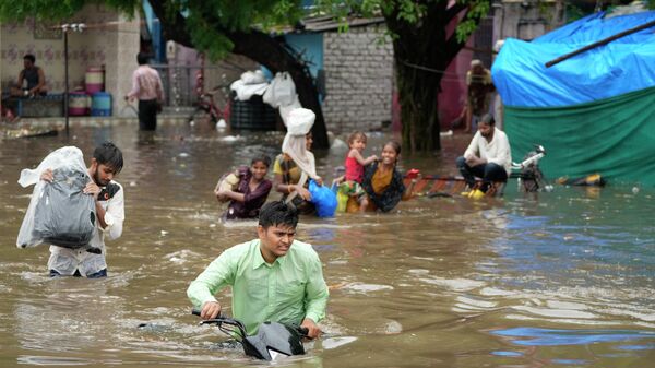 People wade through a flooded street after heavy rains in Ahmedabad, Friday, July 8, 2022. India's monsoon season runs from June to September - Sputnik International