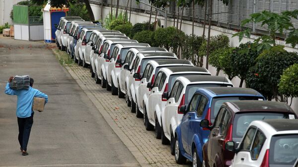 An employee of Mahindra Electric walks past a row of battery operated e20plus cars parked at the company's manufacturing facility in the outskirts of Bangalore, India, Thursday, Nov. 15, 2018. - Sputnik International