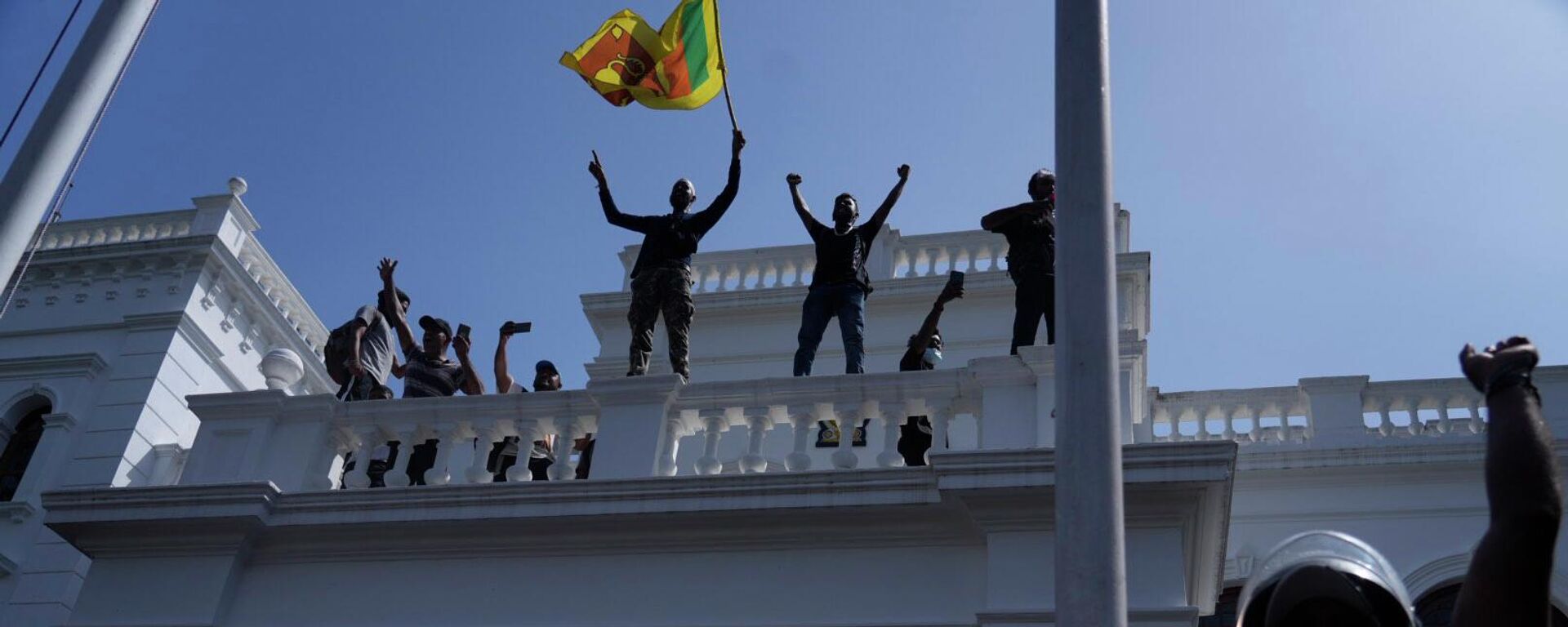 Sri Lankan protesters wave the national flag from the roof of prime minister Ranil Wickremesinghe 's office, demanding he resign after president Gotabaya Rajapaksa fled the country amid economic crisis in Colombo, Sri Lanka, Wednesday, July 13, 2022 - Sputnik International, 1920, 27.07.2022