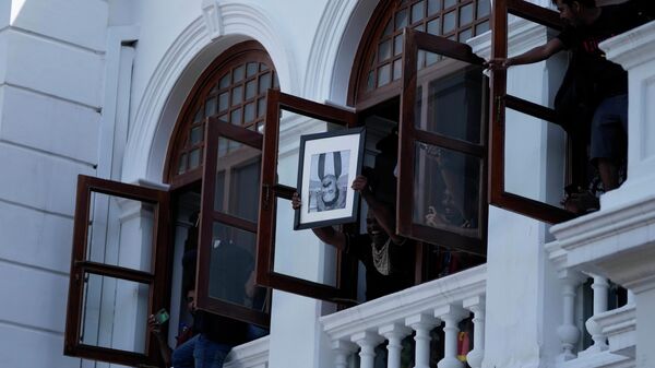 A protester holds a portrait of former Sri Lankan prime minister Mahinda Rajapaksa upside down after storming the Prime Minister Ranil Wickremesinghe's office, demanding he resign after president Gotabaya Rajapaksa fled the country amid economic crisis in Colombo, Sri Lanka, Wednesday, July 13, 2022 - Sputnik International