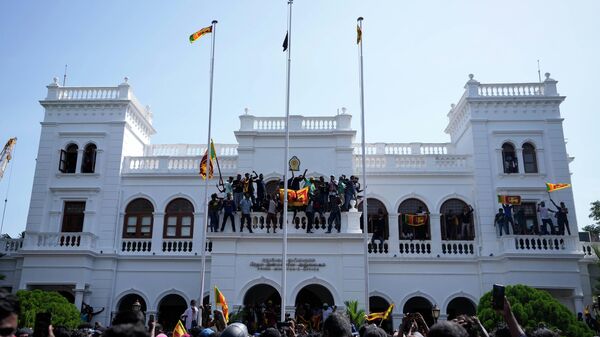 Sri Lankan protesters, some carrying national flags, stand on top of prime minister Ranil Wickremesinghe 's office, demanding he resign after president Gotabaya Rajapaksa fled the country amid economic crisis in Colombo, Sri Lanka, Wednesday, July 13, 2022. - Sputnik International