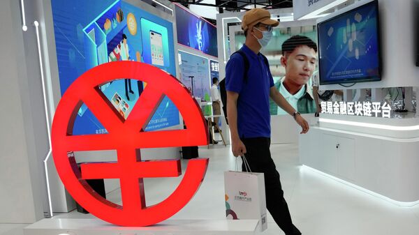 A visitor passes by a logo for the e-CNY, a digital version of the Chinese Yuan, displayed during a trade fair in Beijing, China, Sunday, Sept. 5, 2021 - Sputnik International