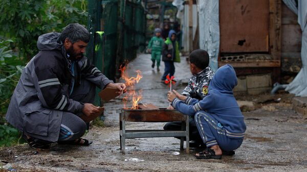A displaced Syrian family warms themselves around a fire at a refugee camp in the southern port city of Sidon, Lebanon, Wednesday, Jan. 19, 2022 - Sputnik International