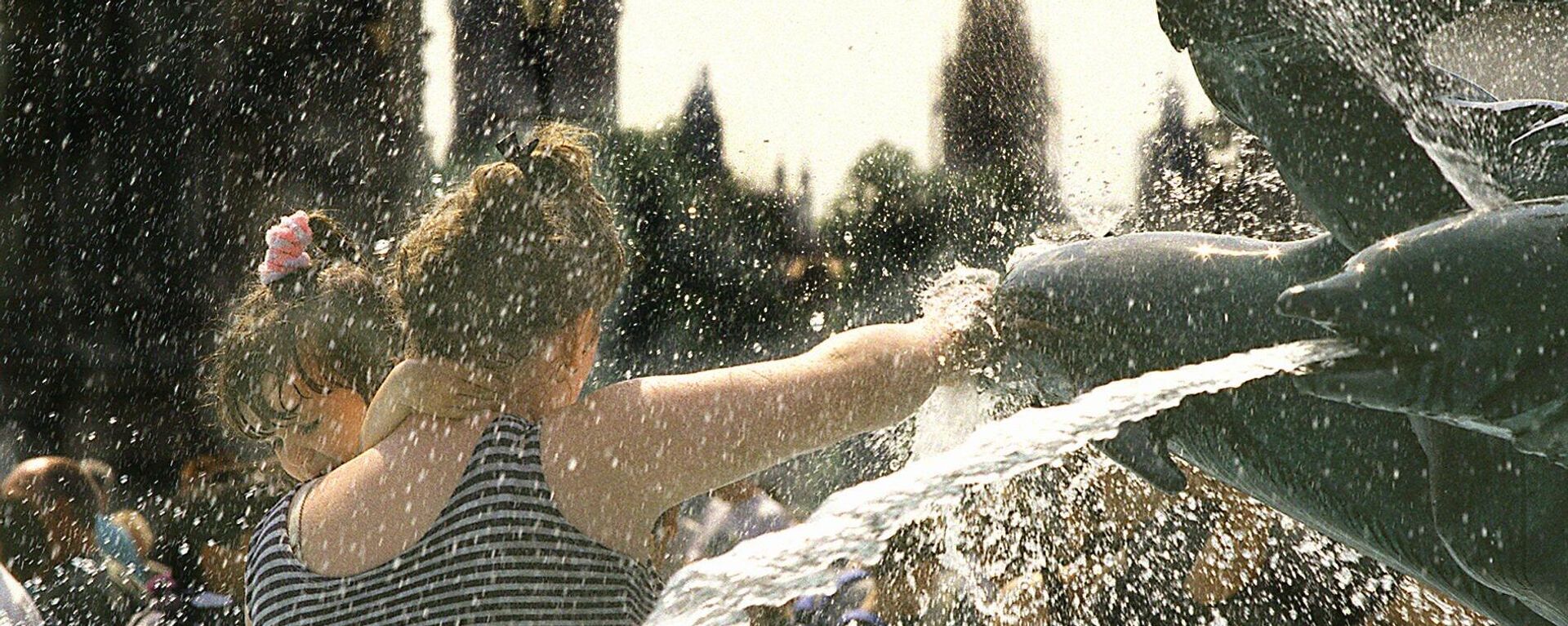 An unidentified mother gives her small child a freshening dip in one of the dolphin fountains in  London's Trafalgar square Saturday August 12, 1995 - Sputnik International, 1920, 11.07.2023